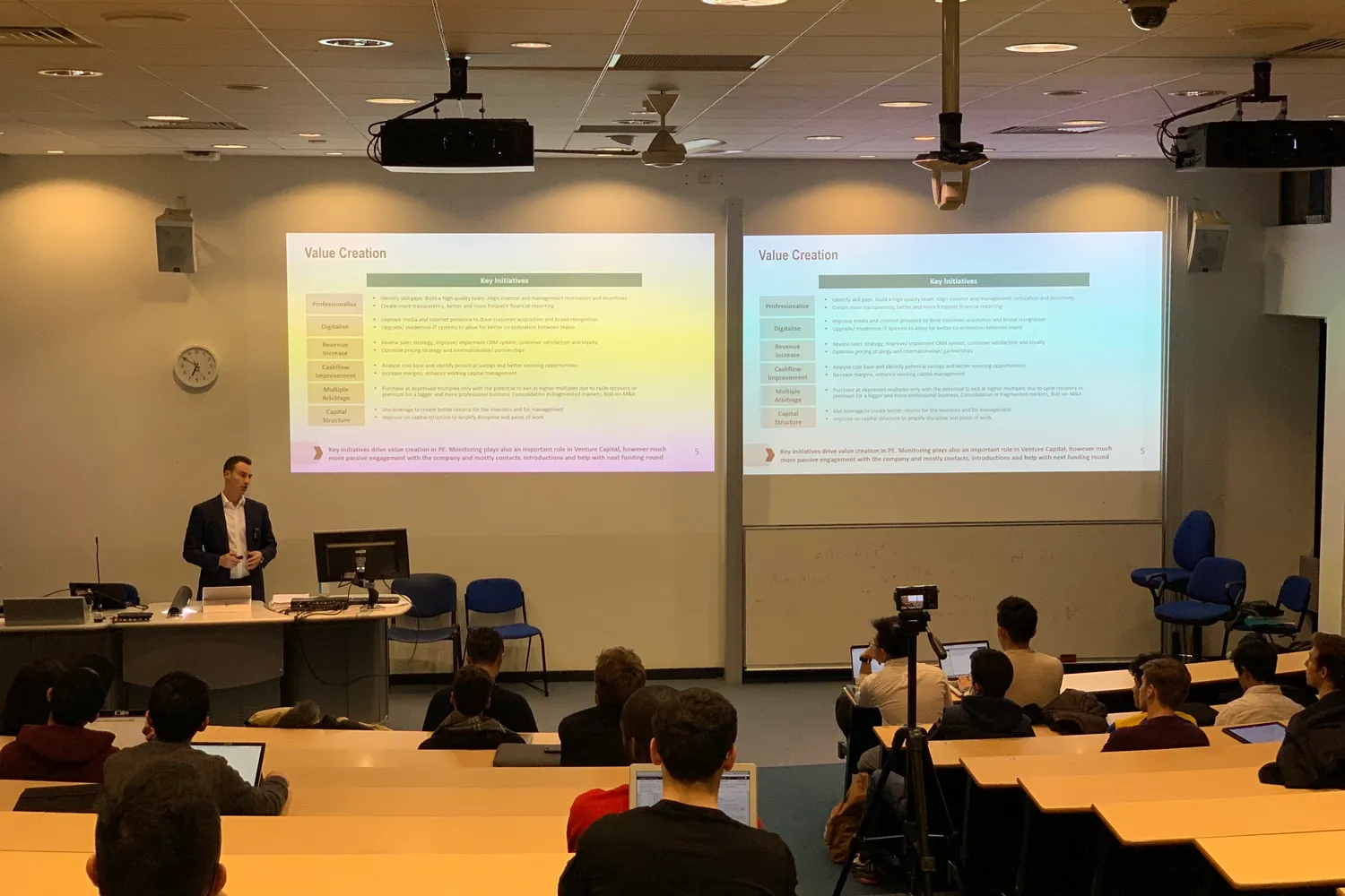 Alexej Pikovsky lecturing in front of two slides titled Value Creation