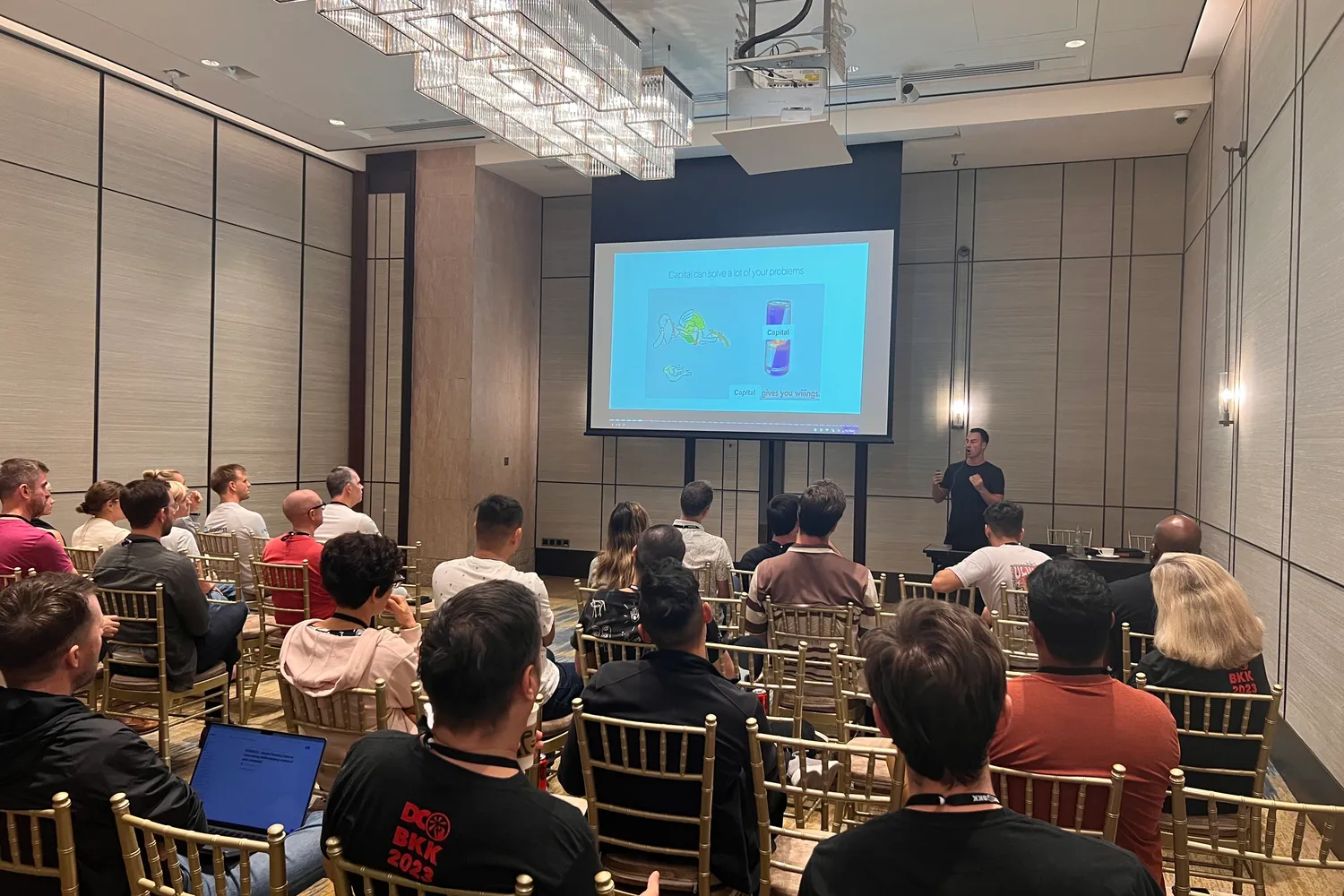 Alexej Pikovsky on stage in front of a full room at the Dynamite Circle conference in Bangkok